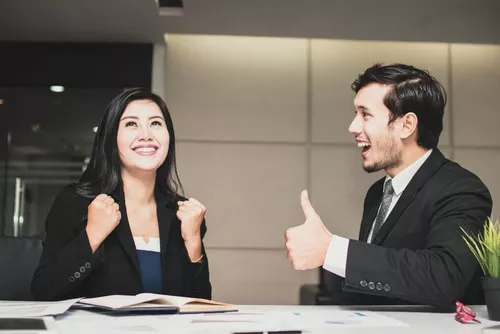 Man giving female colleague a thumbs up 